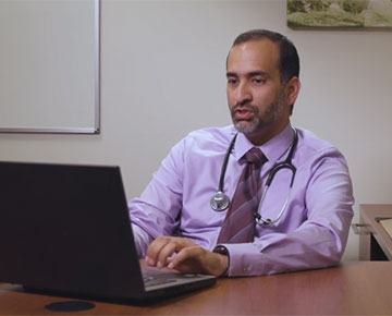 Physician using a laptop at his desk.