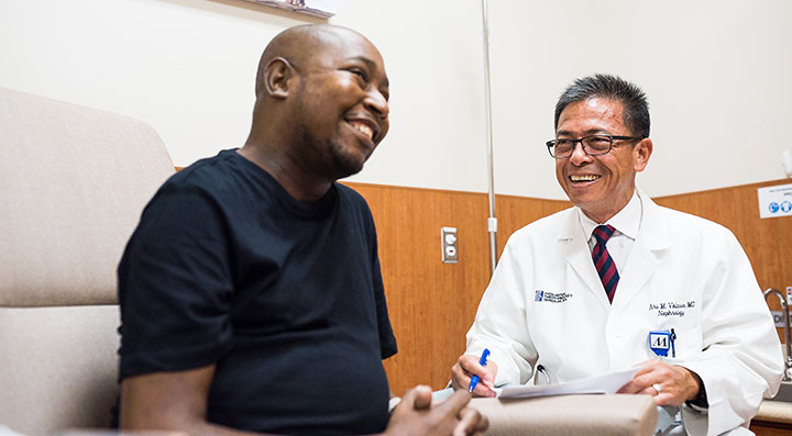 Smiling patient sitting in a chair next to a physician