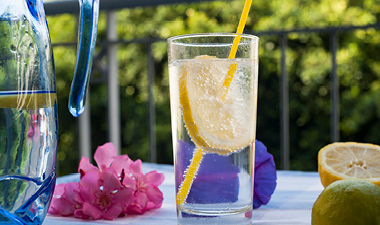 Clear drinking glass of lemon water sitting on a table